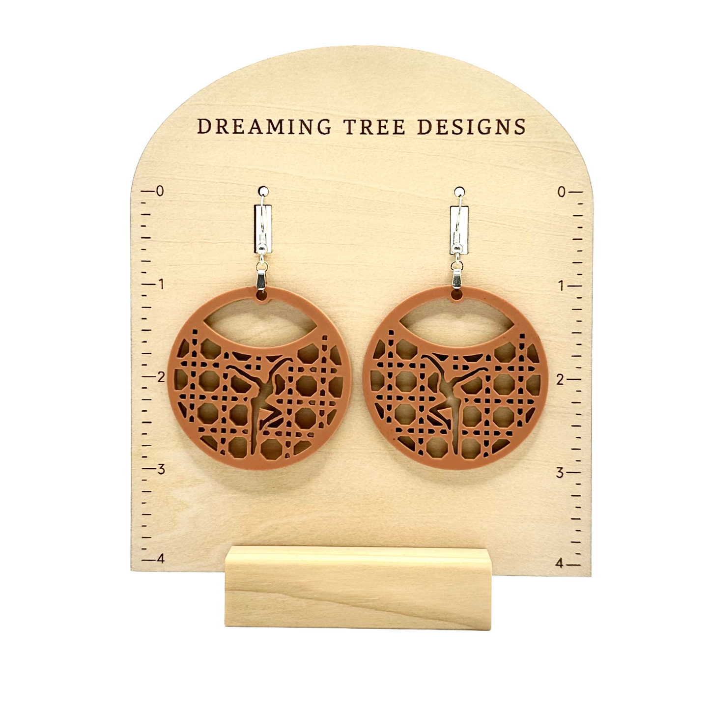 a pair of wooden earrings sitting on top of a wooden stand