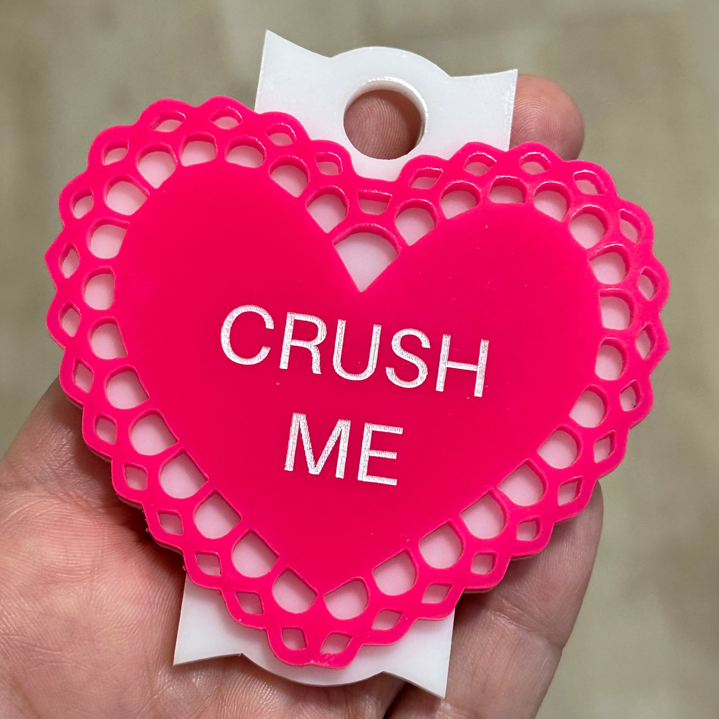 a person holding a pink heart with the words crush me on it