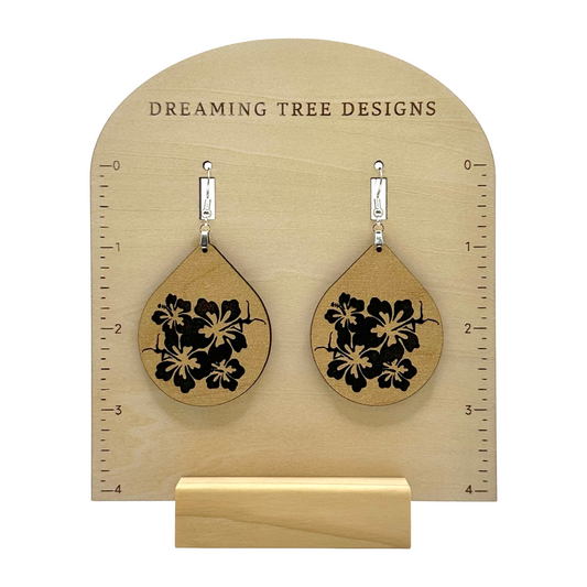 a pair of wooden earrings with black flowers on them
