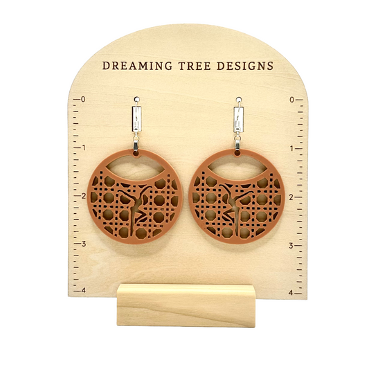 a pair of wooden earrings sitting on top of a wooden stand