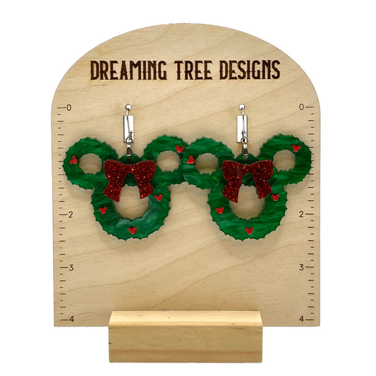 a pair of christmas wreath earrings on a wooden stand